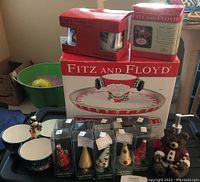 Photo showing Fitz and Floyd ceramic dishware including a Santa-themed dish, dual salt and pepper shakers, sugar and creamer set, snowman candy dish, set of ten glass ornament place card holders, and a teddy bear ceramic soap dispenser.