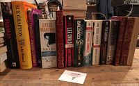 Photo showing 15 books in a row with visible titles and authors including Rankin, Grafton, Lee Child, Baldacci, Connelly, and classic titles.