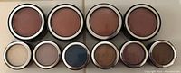 Top-down view of makeup powders in round containers showing four blush colors and six eye shadow colors.
