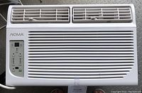 Front view of Noma window air conditioner showing white vented front panel with control buttons and digital display on left side.