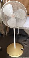 Front view of vintage oscillating pedestal fan with mesh cage and missing paint on base