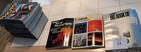 Stack of 98 photo magazines alongside three fully illustrated photography books laid flat showing covers.