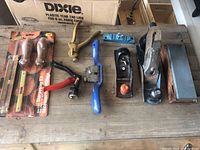 Lot on wooden surface showing wood planes, sharpening stone, sharpening kit, and tooth setting tools including packaging
