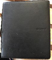 Black Sony e-reader case showing some surface wear and Sony logo on front