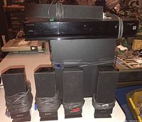 Full view of Sony surround sound system with AV receiver, subwoofer, five satellite speakers with cables wrapped, all placed on a table.