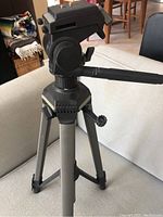 Front view of camera tripod showing head, pan handle, and tripod legs.