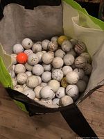 Large reusable FRESHCO shopping bag filled with used golf balls, showing balls of various degrees of dirt and scuffing.