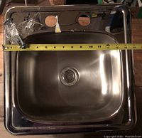 Top-down view of stainless steel sink with measuring tape showing 15 inches total width.