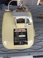 Top view of beige Mastercraft wet stone sharpener showing label with specifications and tool rest over grinding wheel.