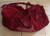 Red mesh carrying bag for karate gear on tiled floor