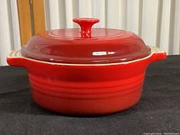 Side front view of the red covered casserole dish with lid on black background