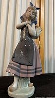 Full view of the Lladró Natures Bounty figurine showing the girl in traditional dress with a basket.