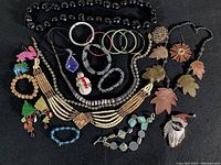 Photo of entire assortment of costume jewelry pieces including necklaces, bracelets, brooches, and earrings on black background.