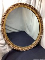 Full view of the oval mirror showing the entire frame and reflective glass.