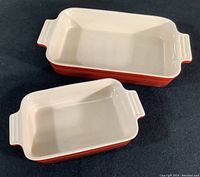 Top-down view showing two rectangular red and cream casserole dishes of different sizes.