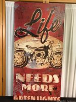 Full view of the rectangular canvas print showing the motorcycle image and text 'Life needs more green lights' on a red background, mounted on a wood frame.
