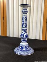 Full view of tall blue and white ceramic candlestick showing overall shape and detailed decoration.