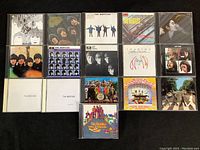 Photo showing full collection of 16 CDs arranged in 4 rows, with identifiable Beatles and John Lennon albums.