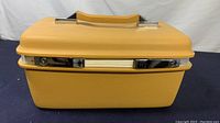 Front view of the vintage hard shell beauty case showing the harvest gold color and chrome trim with key lock.