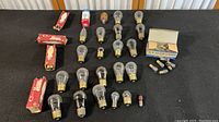 Wide shot of 30 vintage bulbs on black cloth including boxed G-E glow lamps and loose bulbs of several sizes and styles