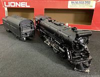Front and side view of Lionel die cast steam locomotive and tender against original red box with label