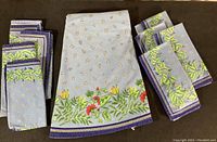 Photo showing folded napkins with a floral pattern on a blue background, arranged in two stacks.