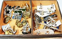 Storage box holding all the cufflinks and buttons with visible compartments, minor wear on the box