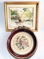Photo showing both framed art pieces together, the signed 12x14 painting and the smaller oval bird needlepoint.