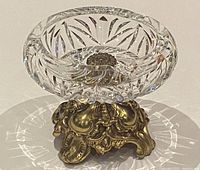 Top-down front view of clear pinwheel cut crystal ashtray on ornate cast metal base showing reflective details and intricate cut crystal design.