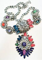 Full view of the chunky vintage necklace showing the symmetrical arrangement of clear crystal clusters and colorful marquise-shaped beads with a large central pendant.