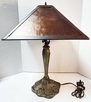 Front view of the vintage mission style table lamp showing its metal shade and floral detailed base.