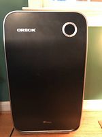 Front view of Oreck air purifier showing full front panel with Oreck logo and circular control knob.