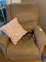 Front view of beige microfiber lift chair with decorative pillow and power cord
