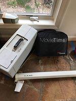 Overview of projector, screen housing tube, and carrying case on floor