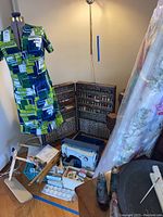 Wide view of sewing machine, dress form with dress, thread cabinet, fabric rolls and accessories