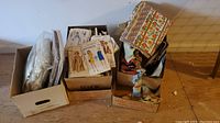 Lot of three boxes containing sewing patterns, assorted fabric pieces with multiple colors and floral prints.