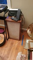 Photo showing one KLH Model Six speaker with wood veneer and fabric front grille, along with Roku SoundBridge M500, Realistic stereo receiver STA-12 and remote, and Terk Edge antenna on top, placed on a small wooden table.