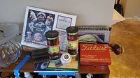 Photo showing Titleist golf balls box, baseball, framed New York Mets memorabilia, and sports cards on a table.