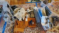 Top-down view showing Millennium Falcon, AT-AT Walker, and various brown playset bases with some figures and accessories scattered around.