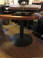 Side view of wooden tabletop on black metal pedestal base