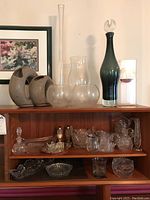 Full view of top shelf and middle shelf showing ceramic vases, various glass vases, frosted bowls, and cut glass items
