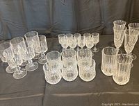 Overview of entire assortment of crystal glasses arranged on black cloth backdrop showing all glass types.