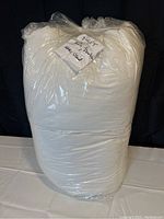 Photo of a white full/double duvet in a clear plastic bag with a handwritten note attached.