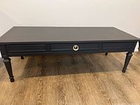 Full view of the solid wood coffee table painted ash color with original hardware showing rectangular shape and decorative drawer trim.
