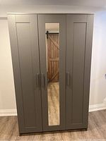 Exterior front view of closed wardrobe showing three doors and center mirror