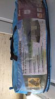 Photo of the blue carry bag with the tent packaging label showing tent image and dimensions.