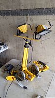 DeWalt two work lights mounted on yellow tripod with circular saws on table