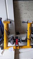 Full-frame image showing yellow bike trainer frame with clamps for bike wheel attachment