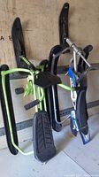 Photo of two GT snow racers, one blue and one green, showing their seats, skis, and handlebars.