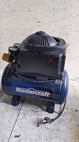 Side view of Mastercraft air compressor showing brand label, pressure gauge, and power cord